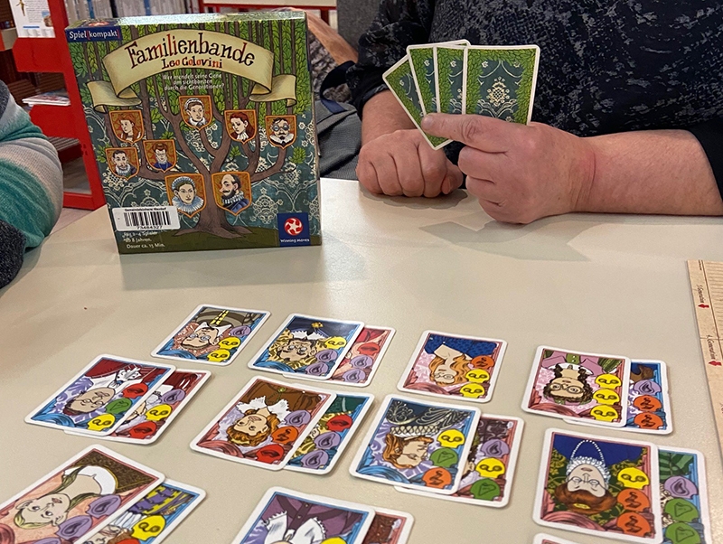 Foto vom Spieleabend. Auf dem tisch liegende Karten swoei die Verpackung eines Gesellschaftsspiels sind zu sehen