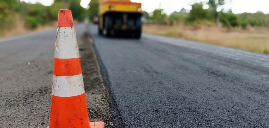 Bild Asphaltarbeiten Raupe planiert Fahrbahn mit Polygon im Vordergrund