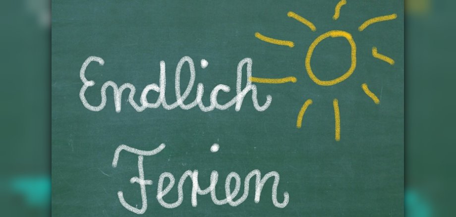 Grafik einer Tafel mit der Aufschrfit aus weißer Kreide "Endlich ferien"