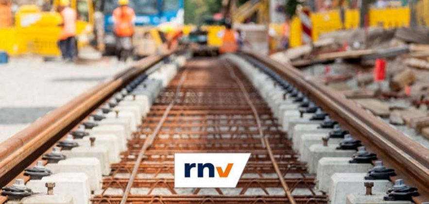 Foto einer Bahnschine, die in einem neu angelegten Gleisbett verlegt wurde mit Logo des rnv