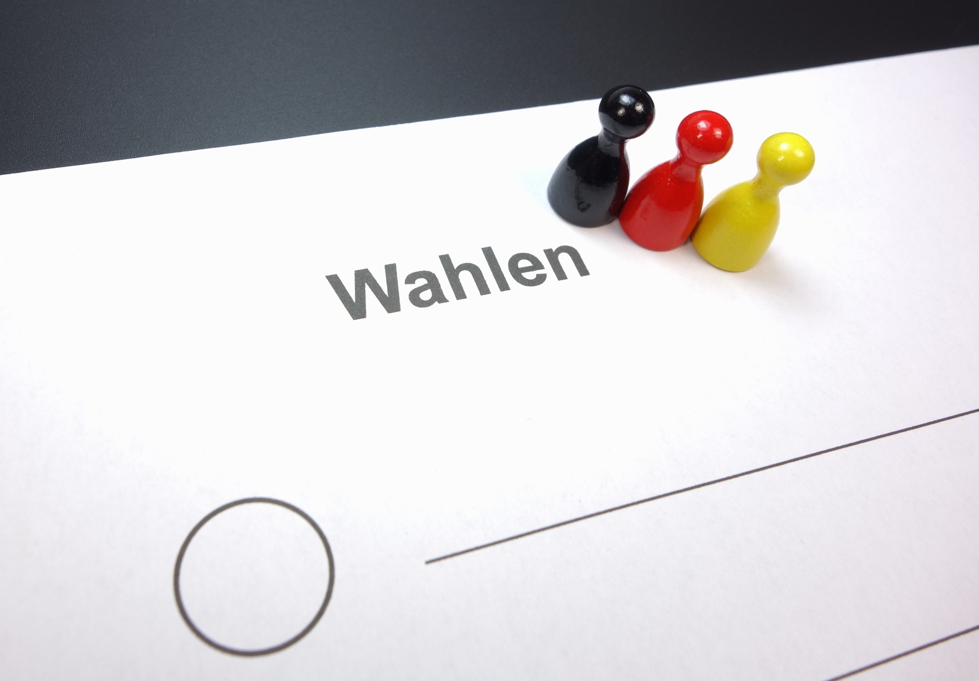 Teaserbild zu Wahlen auf dem steht "Wahlen" ein Kreis eingezeichnet  ist mit einer Linie und schwarz rot gelbe figuren
