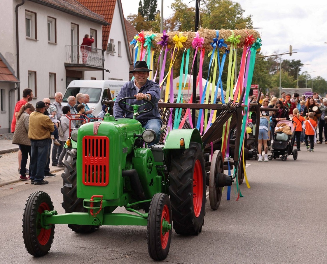 Foto vom Kerweumzug in Maxdorf. Traktor mit Fahrer zieht den Kerwekranz