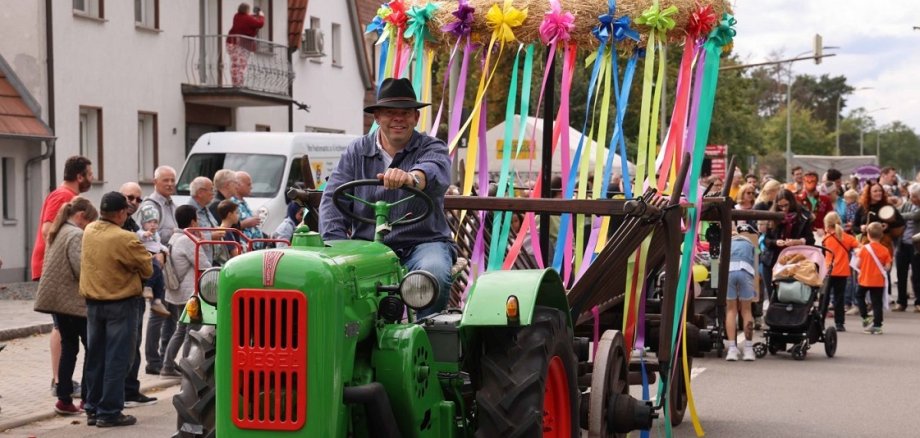 Foto vom Kerweumzug in Maxdorf. Traktor mit Fahrer zieht den Kerwekranz
