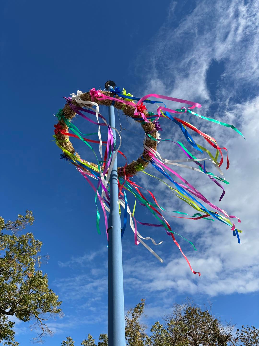 Foto vom Kerwekranz am Mast, vor blauem Himmel mit leichter Bewölkung