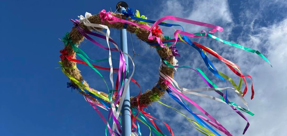 Foto vom Kerwekranz am Mast, vor blauem Himmel mit leichter Bewölkung