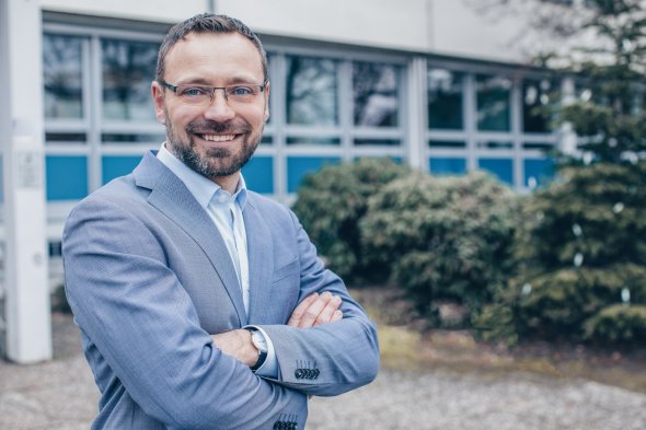 Portrait Foto des Bürgermeisters der VG Maxdorf André Voges, im Hintergrund unscharf das Rathaus Maxdorf